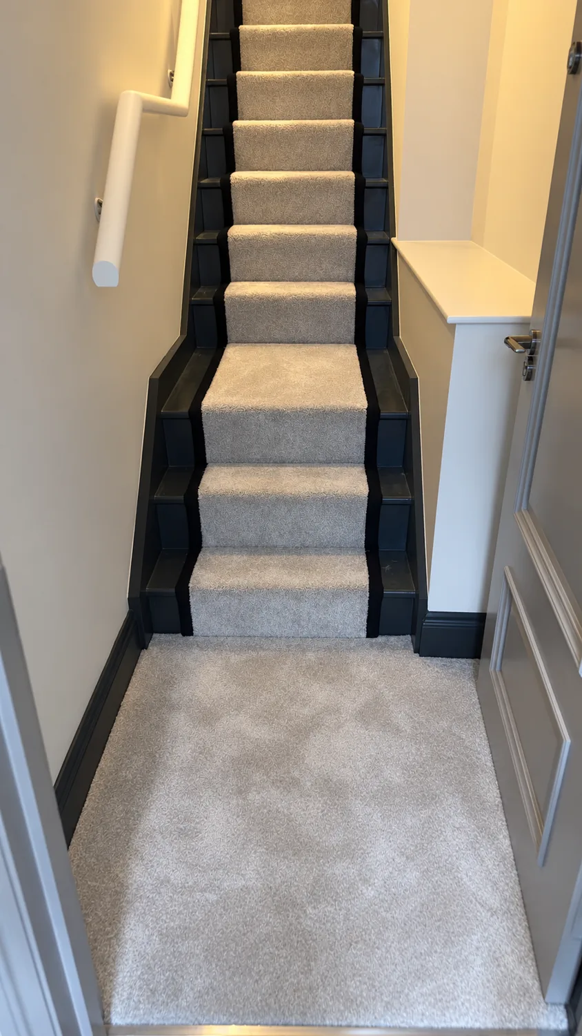A plush grey runner framed by dark stair sides and black binding.